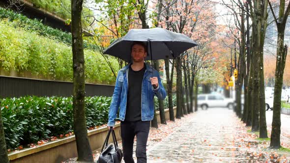 Man holding an umbrella and walking on street