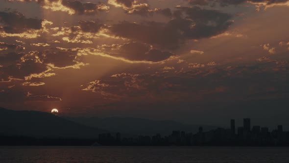 Sun rises from mountains over Vancouver Skyline with beautiful clouds, Time lapse