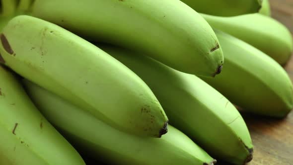 {Bunch of fresh green healthy unripe mini bananas on wooden background 