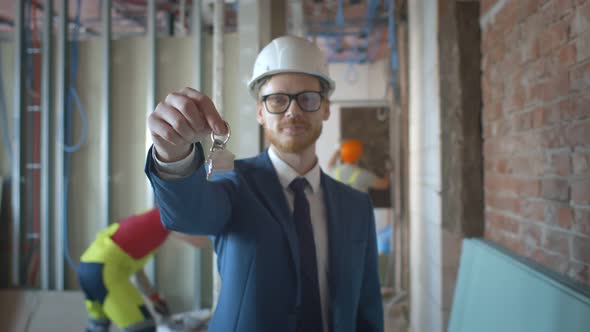 Happy Businessman Holding Keys on Construction Site