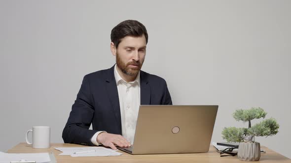 Video call concept, young good-looking man wearing suit and glasses is using a laptop