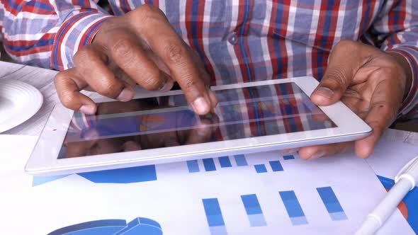 Man's Hand Analyzing Financial Data on Digital Tablet at Office Desk,