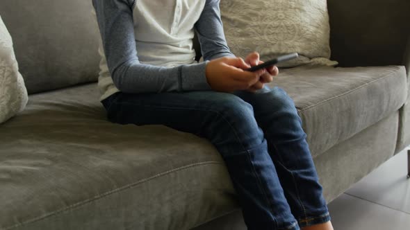 Front view of Caucasian boy playing game on mobile phone in lobby at hospital 4k