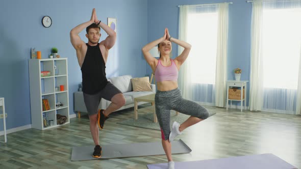 Man and Woman Practice Basic Yoga and Have Fun at Home