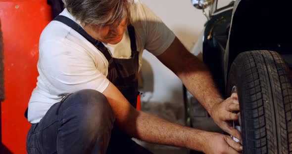 Male mechanic fixing car tire