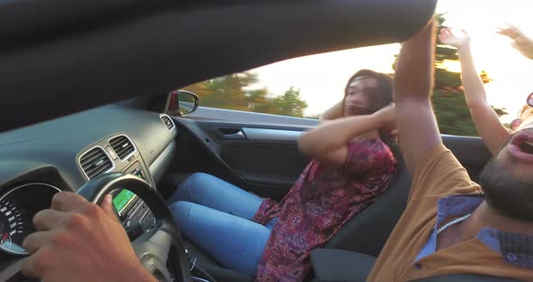 Handsome black man partying with friends while driving in convertible