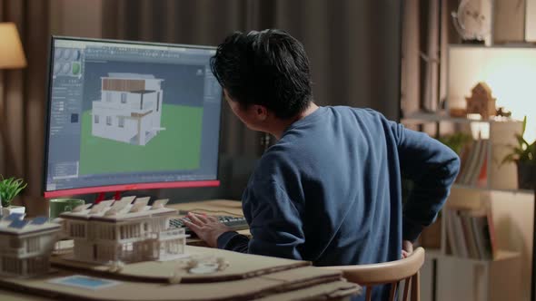 Asian Male Engineer Having A Backache While Designing House On A Desktop At Home