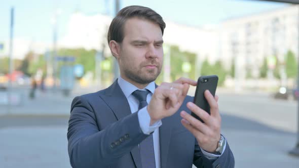 Businessman Browsing Internet on Smartphone Outdoor