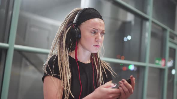 Young Attractive Woman with Dreadlocks Use Smartphone Listening Music on Headphones