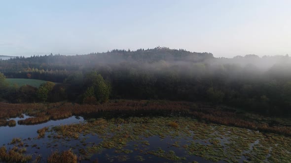  Aerial View of a Lake with Aquatic Plants, Forests and Chapel in the Background 4K