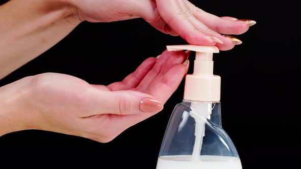 Female Hands Pushing Dispenser and Using Liquid Soap on Black Background