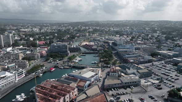 Aerial shot over the city, the river with white yacht and bridges with cars in Bridgetown, Barbados