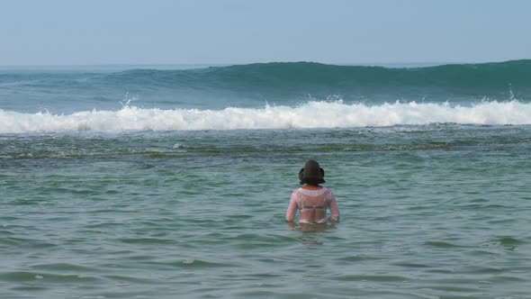 Young Lady in Green Hat Stands in Middle of Tropical Ocean