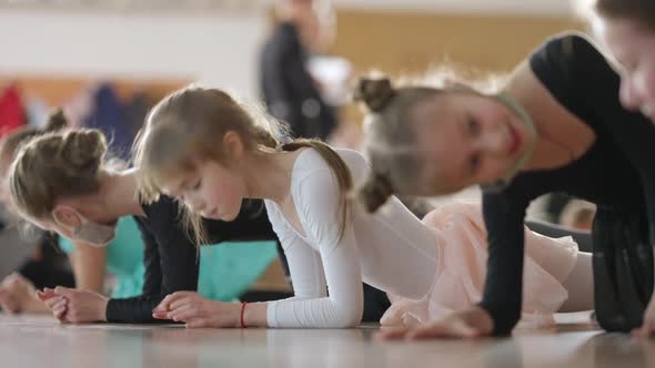 Charming Cute Caucasian Girl Standing in Plank Position with Children in Dance Studio