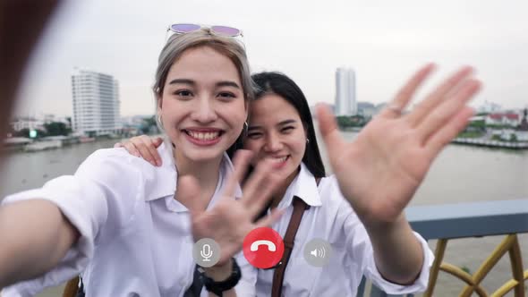 Happy Asian couple lesbian video call talking with friends during travel on vacation summertime.