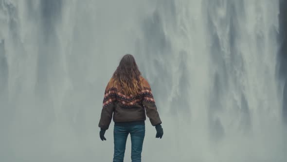 Woman standing on rock against amazing waterfall