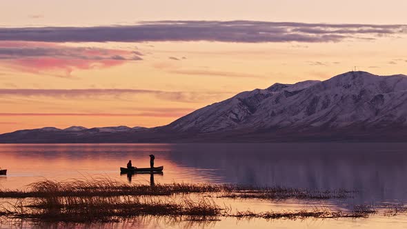 People floating in canoe on Utah Lake as one stands up in the boat