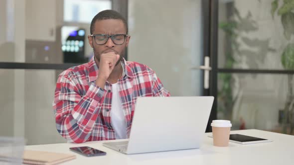 African Man Coughing While Using Laptop