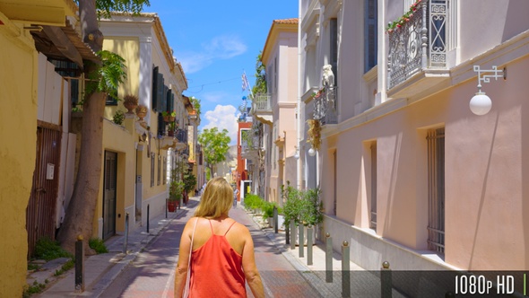 Back view of young tourist woman walk down small Greek road in Athens, Greece