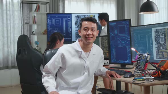 Asian Man Smiling Charmingly Looking At Camera. Young Intelligent Male Scientist Working In Office