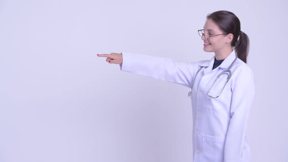 Profile View of Happy Young Beautiful Woman Doctor Pointing Finger