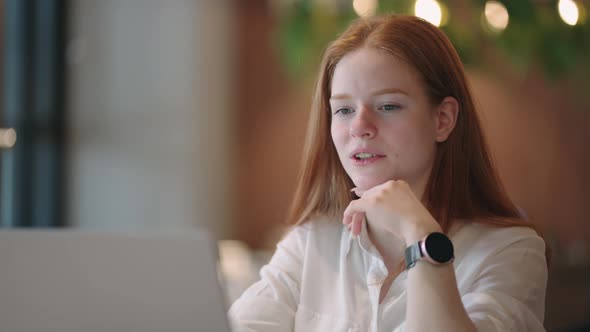 Focused Redheaded Woman Distance Teacher Online Tutor Wear Headphone Conferencing on Laptop