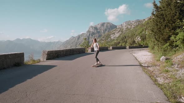 Hipster dreadlocks woman in sun rays longboarding on mountain background riding skateboard