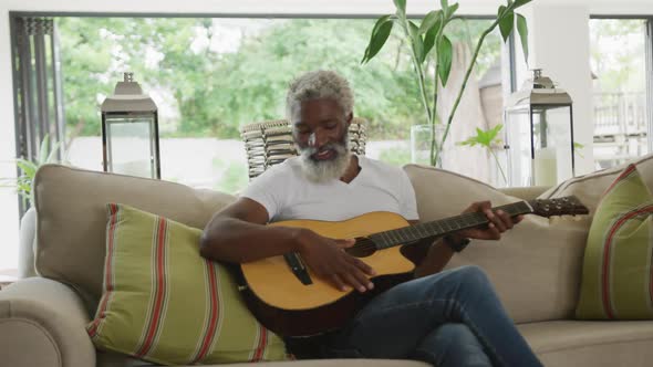 Video of sad african american senior man playing the guitar