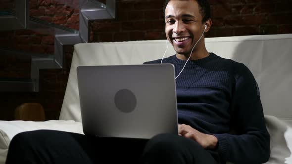 Web Video Chat on Laptop By African Man at Night Headphones