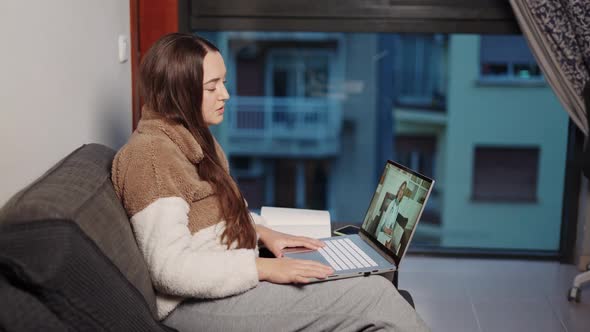 Young Pregnant Woman Attending Virtual Session with Doctor on Laptop While Sitting on Sofa at Home