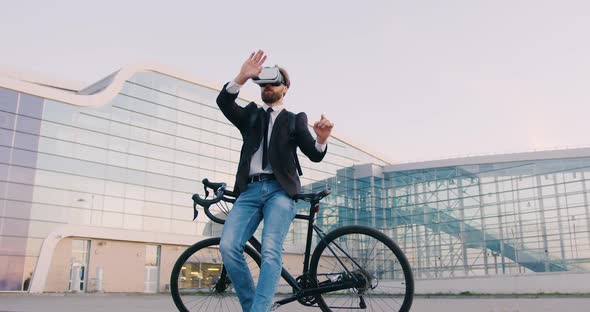 Businessman in Virtual Reality Headset Standing Near His Bicycle and Working on Imaginary Screen 