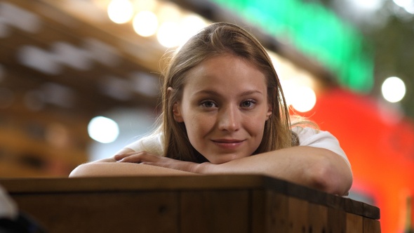 Lonely cute girl lying on the table and looking at you smiling.