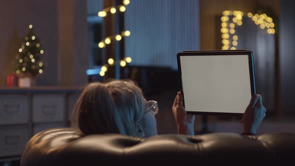 Back View of Woman Laying on Sofa Watching a Movie on Her Digital Table