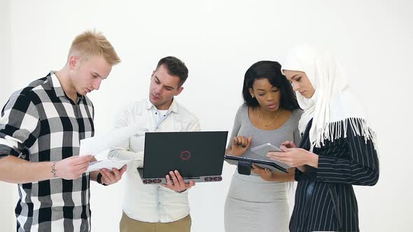 Young Two European Men and Two African American and Muslim Women Using Laptop, Tablet PC