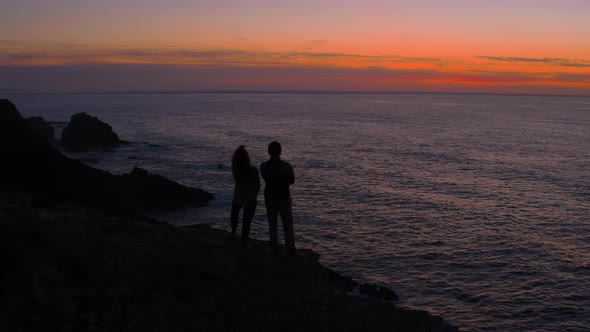 Silhouette of Couple Walk on Cliff Edge at Sunset