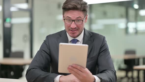 Middle Aged Businessman Doing Video Chat on Digital Tablet