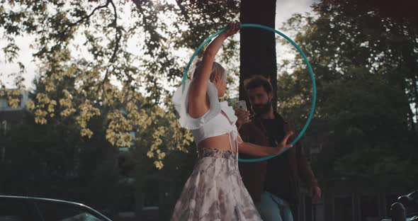 Woman Dances with Hula Hoop while man films with Phone