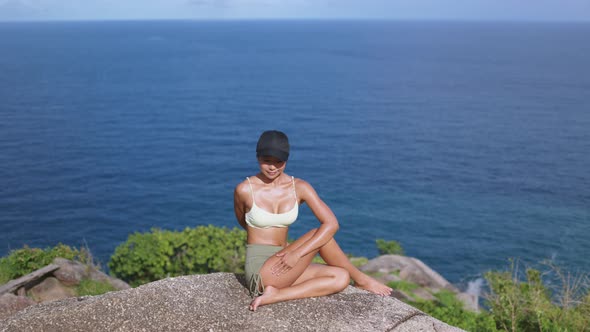 Young Asian Woman Practicing Yoga on the Cliff of Mountain with a Sea View