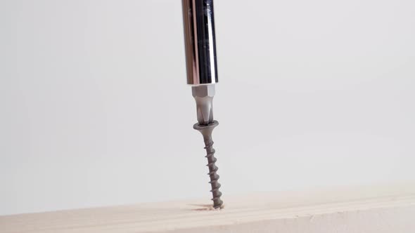 Closeup of a Black Selftapping Screw Being Driven Into a Wooden Beam with a Phillips Screwdriver