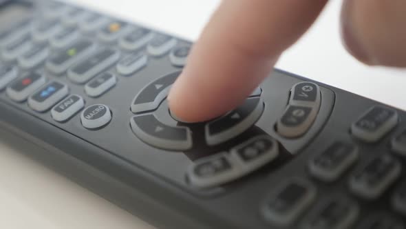 Button pressing on  TV remote control close-up footage