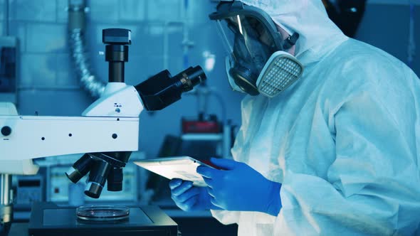 Laboratory Specialist is Operating a Tablet and a Microscope