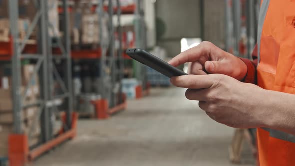 Unrecognizable Warehouse Worker Using Mobile Phone