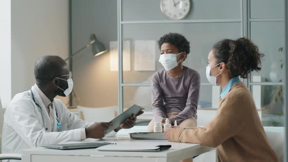 African American Pediatrician in Mask Giving Consultation to Kid and His Mother