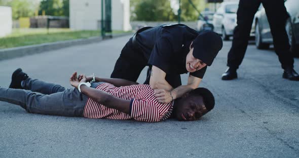 Angry Police Officer Interrogating African American Guy on Ground