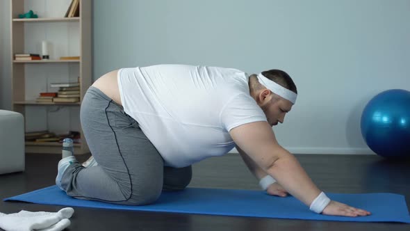 Motivated Chubby Male Stretching With Effort at Home, Will Power, Weight Loss