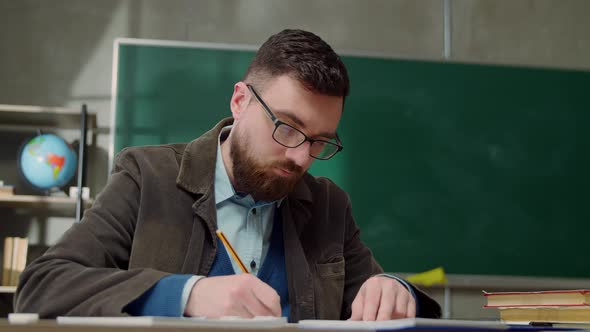 Young Teacher Man Checks Homework Students Sitting in Classroom at School
