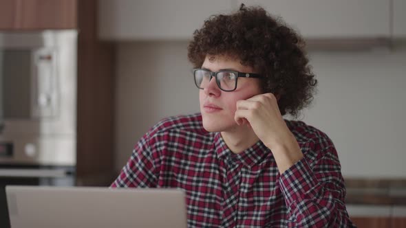 Brooding Serious Curly Freelancer Man Sit at Table in Comfortable Home Office Room Work on Laptop