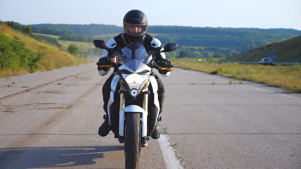 Man in Helmet Driving Powerful Sport Motorbike at Highway with Beautiful Background