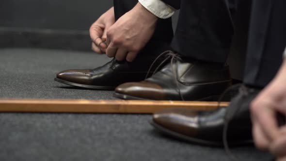 A man tying the laces on  shoes. 