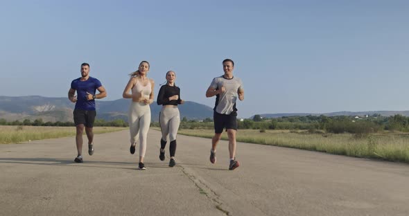 Multiethnic Group of Athletes Running Together on a Panoramic Countryside Road